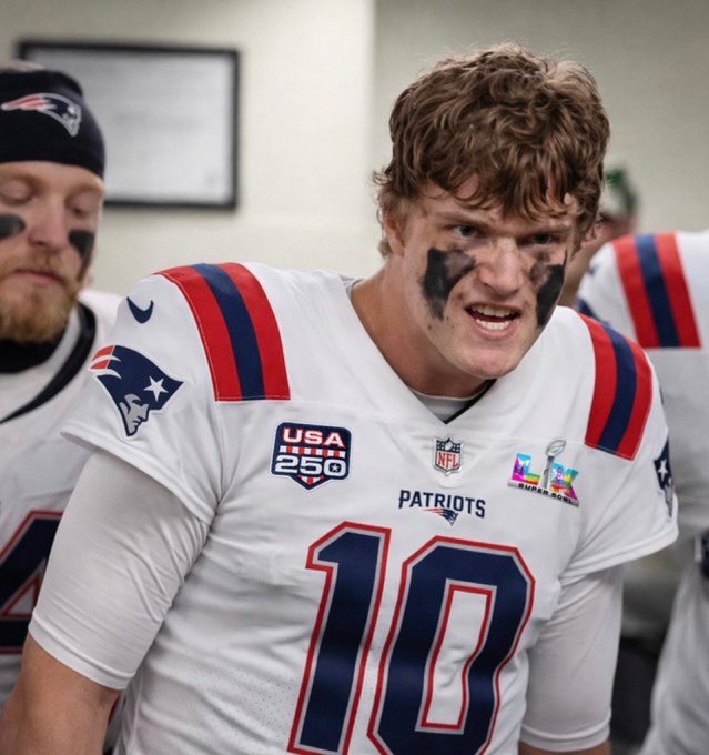 A New England Patriots football player wearing jersey number 10 with a USA 250 patch stands in a locker room with eye black on his face.
