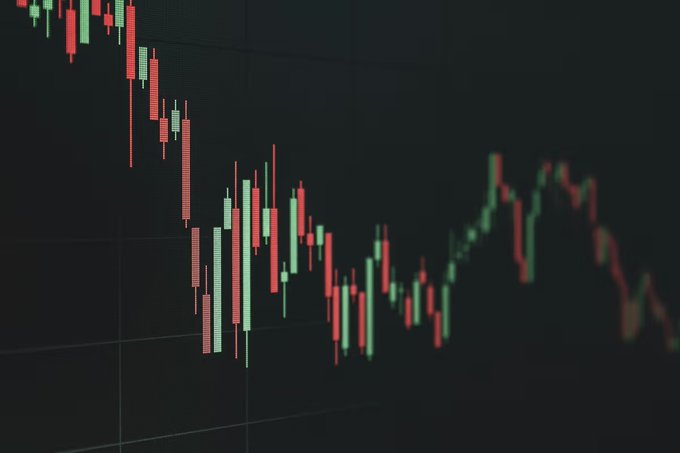 This image shows a financial chart with red and green candlesticks, illustrating a volatile market trend that is consistent with the post's description of AI stocks attracting capital while Bitcoin and the crypto market struggled. The visual depicts the ups and downs of market performance, reflecting the contrasting performance between different asset classes.