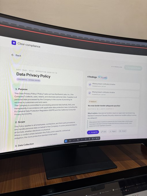 A curved monitor displaying a document titled 'Data Privacy Policy' with a 'Clear compliance' interface showing '4 findings' and breach notifications.