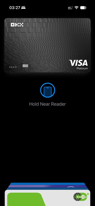 A smartphone screen displays the Apple Pay setup interface with the text "Hold Near Reader" beneath an OKX Visa Platinum card. This relates to the post about successfully adding the latest U Card from OKX Singapore to a digital wallet, showing the completion of the card setup process.