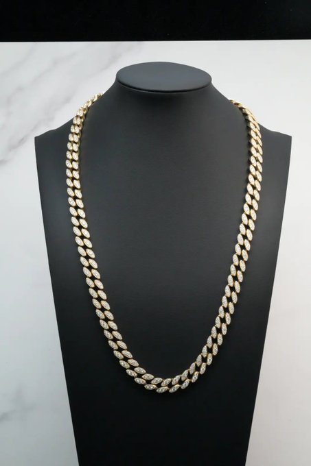 A gold Cuban link chain adorned with diamond-encrusted links is displayed on a black jewelry bust against a marble background, showcasing a luxurious custom piece. The post promotes the jewelry business's custom-made offerings and their willingness to accept cryptocurrency as payment.