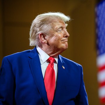 President Donald Trump, wearing a blue suit and red tie, stands in profile near an American flag. The image accompanies news that Trump announced the CFTC is working to bring Hyperliquid, a cryptocurrency exchange, into the US in compliance with regulations, boosting the HYPE token above $70.