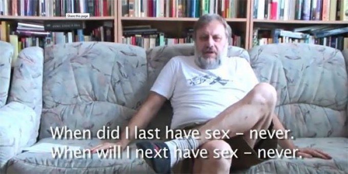 A man sitting on a floral couch in front of a bookshelf with subtitles reading 'When did I last have sex - never. When will I next have sex - never.'
