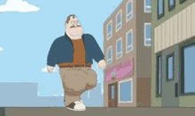 A man in a blue shirt and brown pants walks on the sidewalk, with a pink building and white clouds in the background.