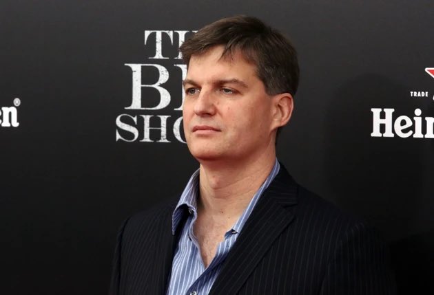 Photo of a man in a dark pinstripe suit and blue striped shirt standing in front of a backdrop reading 'THE BIG SHOW' and 'Heineken'.