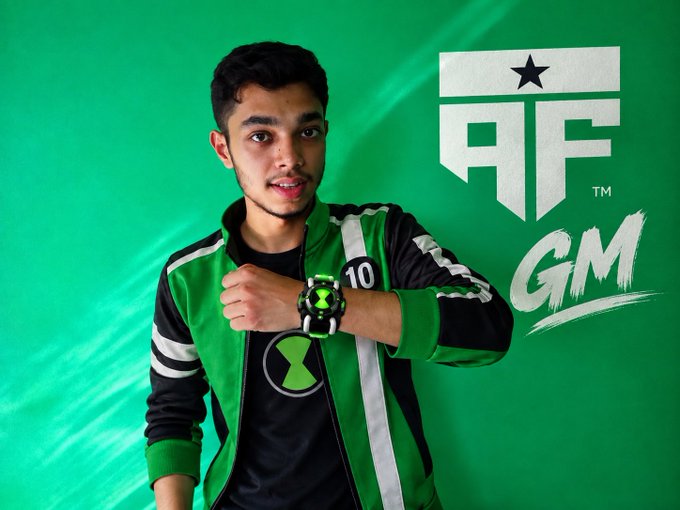 A young man modeling a green and black Ben 10 themed jacket with the Omnitrix logo, posed against a green background featuring 'AF GM' branding.