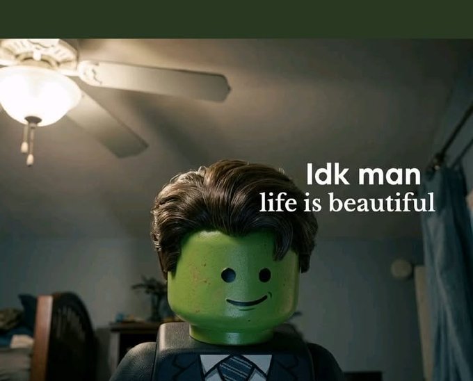A green Lego minifigure head with a brown pompadour hairstyle sits on a torso wearing a tuxedo, with white text overlay reading 'Idk man life is beautiful' against a bedroom background.