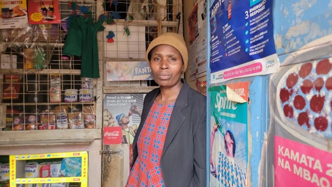 Caroline stands smiling in her shop, surrounded by colorful Coca-Cola ("Taste the Feeling") and Sprite ("DIOR") advertisements, with a poster reading "Need a Break? Grab a hot or cold Coca-Cola!" visible behind her. The image celebrates her successful funding through Geyser Fund's Recoverable Grants program, likely supporting her small business.