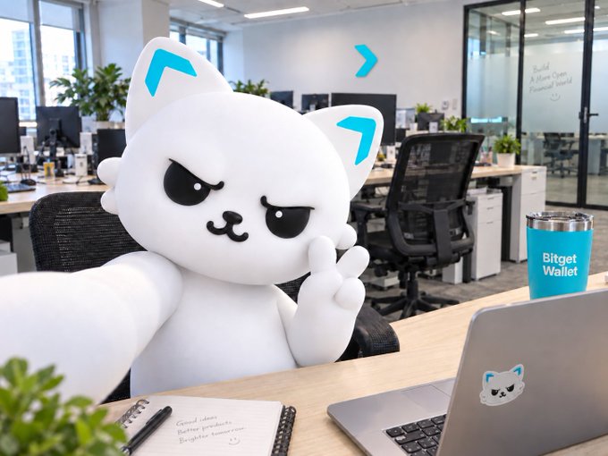 A grumpy-looking mascot character lounges at a modern office desk next to a laptop with its face as a sticker and a blue tumbler labeled "Bitget Wallet," playfully personifying the self-hosted wallet app as an 8-year-old taking a break in a corporate setting.