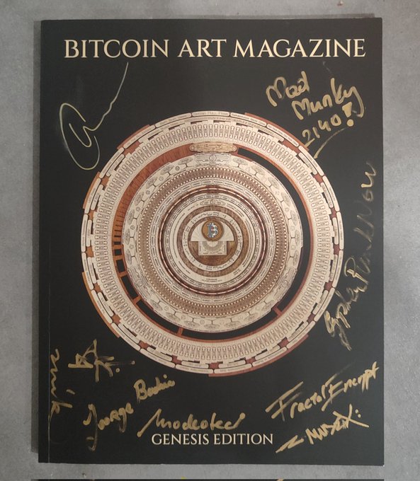 The image features a black book with gold lettering that has been signed by various artists, including @FractalEncrypt, @Jethroe111, @spacebull, and others. The book appears to be a Bitcoin Art Magazine, and the signature of @FractalEncrypt is particularly notable. The post also mentions that this edition of the magazine was released in Genesis Edition.