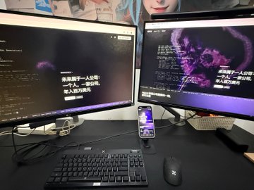 A dual-monitor desk setup with a keyboard, mouse, and smartphone, displaying dark-themed content with Chinese text screens.