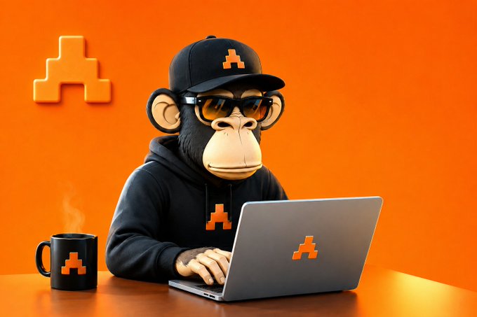 A 3D-rendered monkey character wearing a black hoodie, cap, and sunglasses, typing on a laptop with an orange logo, accompanied by a matching mug and a large 3D logo on the orange background.