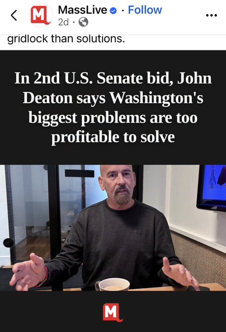 A MassLive social media post features a headline reading "In 2nd U.S. Senate bid, John Deaton says Washington's biggest problems are too profitable to solve," accompanied by a photo of a bald, bearded man in a dark sweater gesturing with open hands at a table with a coffee mug. The accompanying text discusses John Deaton's explanation regarding Democrats allegedly avoiding a floor debate on the CLARITY bill to prevent being exposed on ethics matters.