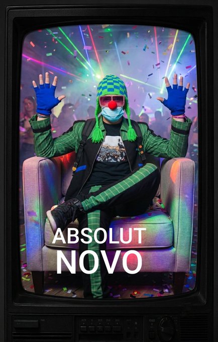 An Absolut Vodka advertisement titled 'ABSOLUT NOVO' showing a person in a clown nose, surgical mask, green knit hat, and sunglasses sitting in an armchair on a TV screen.