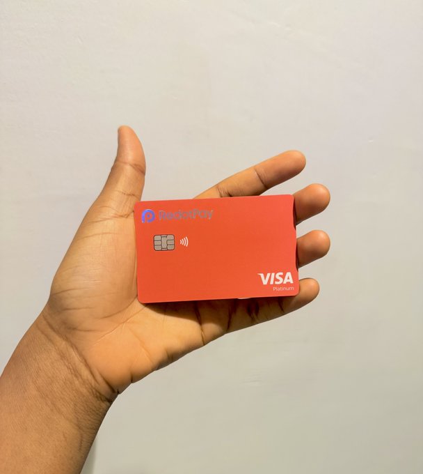 A hand holds up a bright orange "RedotPay" Visa Platinum physical debit card featuring a chip and contactless symbol, matching the post's celebration of finally receiving the long-awaited crypto-backed prepaid Visa card for worldwide ATM withdrawals.