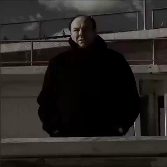 The image shows an adult balding man wearing a hoodie, standing near white railings outside of a building. He appears to be staring out into the distance with a concerned expression. The text at the bottom of the image provides some context about what has happened in the market, specifically stating that over $1.6 billion has been wiped out and there are Bitcoin trading platforms taking a significant hit as well.