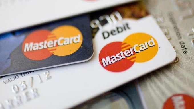 The image shows a close-up view of two Mastercard credit cards placed next to each other. The cards are positioned side by side with their logos prominently displayed, indicating that they belong to the same company. The text "Mastercard" is visible on both cards, and one card has a red logo while the other has an orange logo. The cards appear to be in good condition and ready for use.