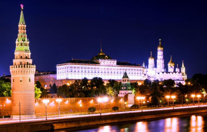 The Moscow Kremlin, including its iconic towers and golden-domed cathedrals, glows against the night sky above the Moskva River. The illuminated Russian government seat visually anchors the announcement of President Putin signing Russia's new crypto market structure law, symbolizing the official state-backed regulatory framework for digital assets taking effect September 1.