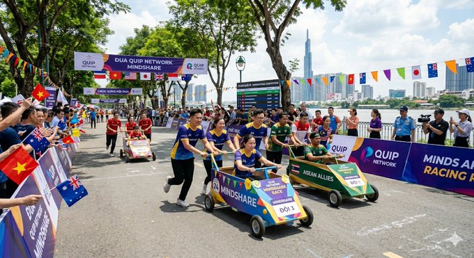 The image shows a group of people racing tricycles down a street, with flags flying above them. The crowd appears to be cheering for the racers as they compete against each other. There are two main groups of people participating in this event - one on the left side and another on the right side of the street. The spectators can be seen watching from various positions along the street, creating an exciting atmosphere.