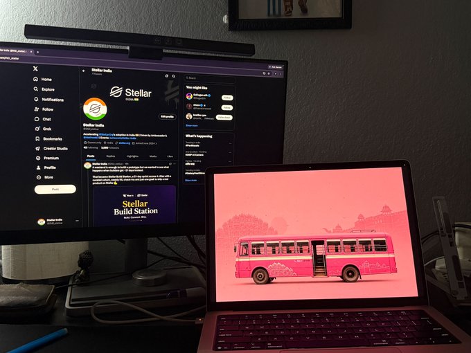A workspace is set up with an external monitor displaying the Stellar (XLM) org homepage and a laptop showing a pink bus illustration, ready for the Stellar Builder Residency event in Jaipur.
