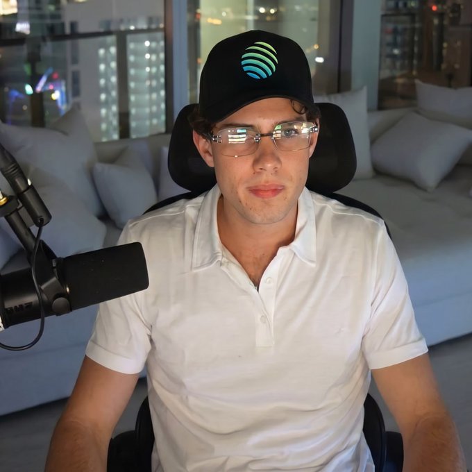 The image features a man wearing glasses, sitting down with his hands resting on his knees. He has a microphone set up behind him, suggesting that he might be preparing for or just finished recording a podcast or live stream. The caption reads "JM! Big week. Wagmi". This phrase is likely related to the content of the audio being recorded by the man in the image.