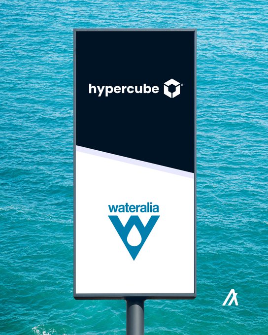 The image features a large sign with the words "Hypercube" and "Wateralia" written on it. The sign is displayed against a backdrop of water, possibly an ocean or a lake. The text on the sign indicates that Hypercube has joined forces with Wateralia for ten years to address global water challenges through innovative solutions. This partnership aims to improve how the world manages water resources by leveraging the expertise and capabilities of both companies.