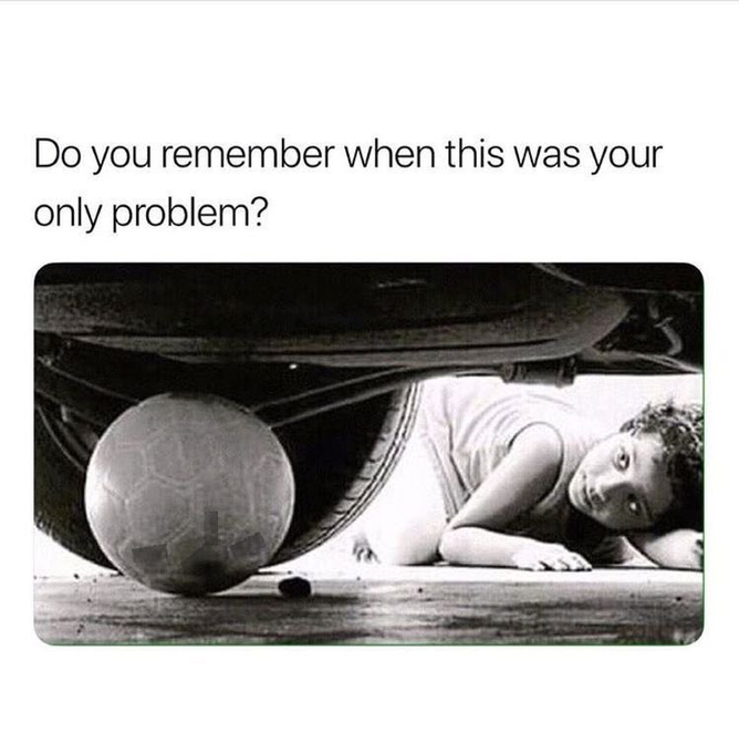 A nostalgic black-and-white photo shows a young boy lying on the ground reaching under a car to retrieve a soccer ball, with the caption "Do you remember when this was your only problem?"