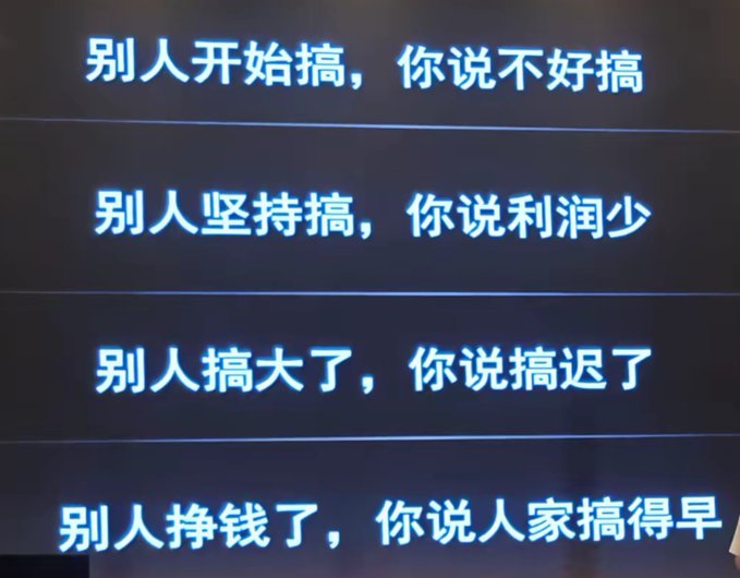 A blue sign with white Chinese text that reads: '别人开始搞，你说不好搞 / 别人坚持搞，你说利润少 / 别人搞大了，你说搞迟了 / 别人挣钱了，你说人家搞得早'.
