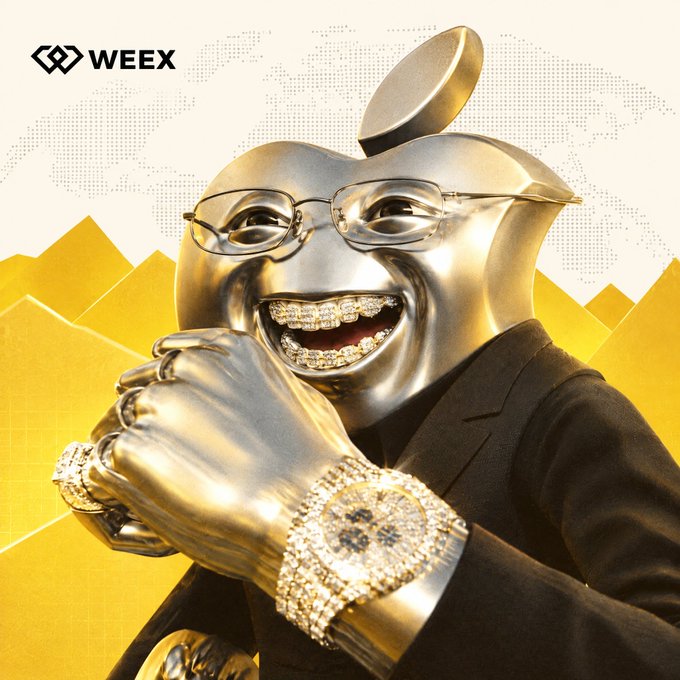 A glossy gold Apple logo character wearing a black suit, glasses, and diamond-encrusted grillz and watch gives a wide, gleeful grin while clasping its hands together in front of a yellow stylized background, with the "WEEX" logo visible in the top left corner, matching the playful "gmmmmmmmmm" caption by exuding an aura of extravagant, drooling excitement over wealth or a juicy opportunity.