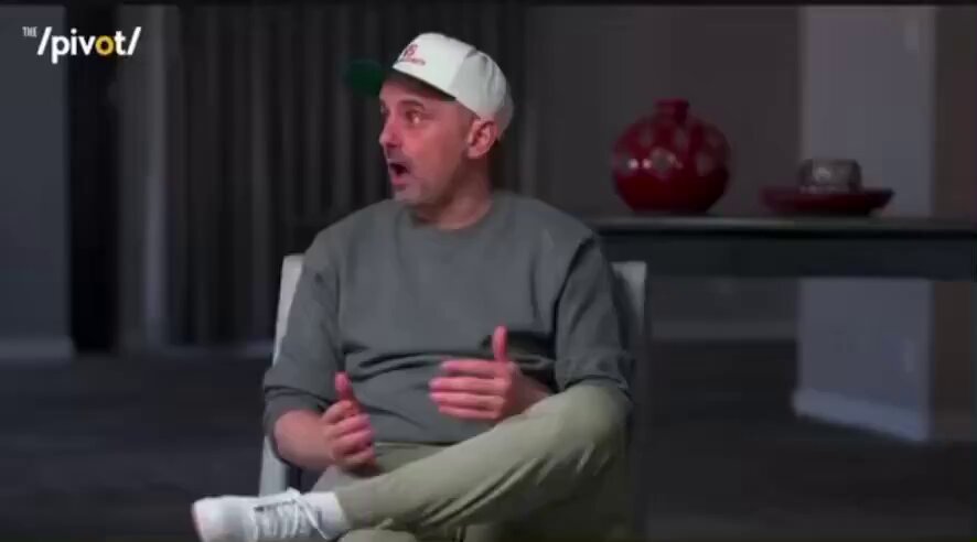 The image features a man sitting comfortably in an armchair, wearing a white cap and dressed casually with his hands placed on his lap. He appears to be deep in thought or having a conversation with someone behind him. In the background, there is a table with two vases placed on it, one red and one brown, adding a touch of color to the scene. The image also includes text that reads "GARY VEE: 'I'M BUYING BITCOIN LEFT AND RIGHT THE LAST 48 HOURS.
I'M SAYING $68K, BUY NOW, FOR 13 YEARS FROM NOW." This adds an element of financial context to the conversation or thought process the man is going through.