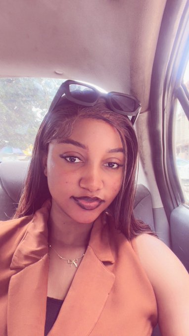 A woman with dark sunglasses perched on her head poses in the back seat of a car, wearing a camel blazer over a black top with a delicate necklace. Her polished, fashion-forward look embodies the intersection of style and innovation, visually echoing her post about merging fashion with Web3 culture beyond just logos on apparel.