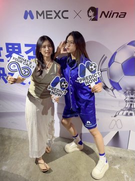 Two women pose at a MEXC x Nina promotional event, wearing blue and white merchandise with soccer-themed graphics and 'PREDICT NOW' text.