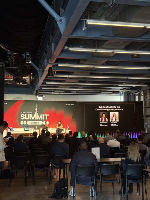 The image shows the SOL/DAI Summit Canada conference, where panelists discuss "Building trust into the Canadian crypto experience" on a large digital screen, visually reinforcing the bullish sentiment toward crypto's future in Canada through an engaged audience of industry professionals.