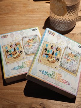 Two boxes of Japanese Pokémon Card Game merchandise (ポケモンカード) featuring Pikachu artwork displayed on a wooden table, seemingly shop or product photos.