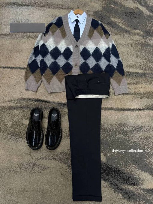 A flat lay fashion outfit featuring an argyle cardigan in navy, cream, and tan over a white collared shirt with black tie, paired with black wide-leg trousers and chunky black boots, displayed on a striped rug—styled for a preppy "Blockfest" look with the watermark "@favys.collection_4.0" visible.