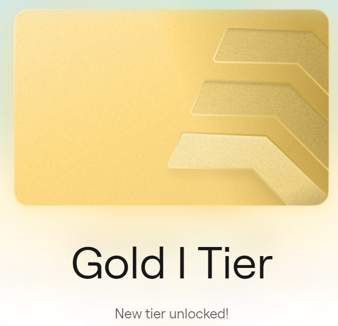 A gold-colored achievement card showing three tiered arrows on the right side with the text 'Gold I Tier' and 'New tier unlocked!' beneath.