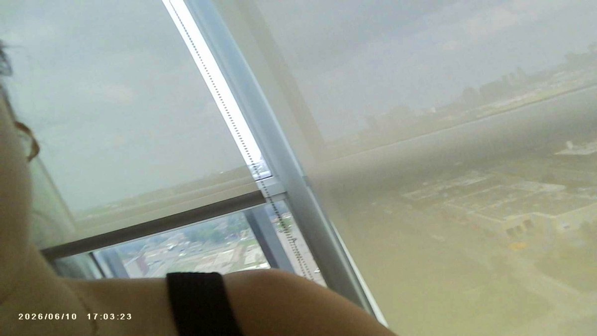 The image shows a person's shoulder with their arm outstretched towards the camera. The background of the photo features a window overlooking an urban cityscape, providing a view of buildings and streets below. The caption for the image reads "We're excited to hack with everyone at @ETHGlobal this weekend! Come meet our newest DevRel @kimcodeashian You'll also see some familiar faces @joannatran_ , @brownmanwonders and @wizrd0x".
