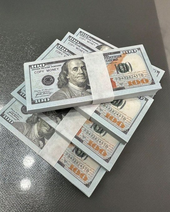 A stack of prop "$100" bills clearly marked "COPY MONEY" and "NOT MOTION PICTURE PURPOSES" rests on a dark surface. The joke undermines the caption's boast about making real money, as the bills are explicitly fake novelty currency.