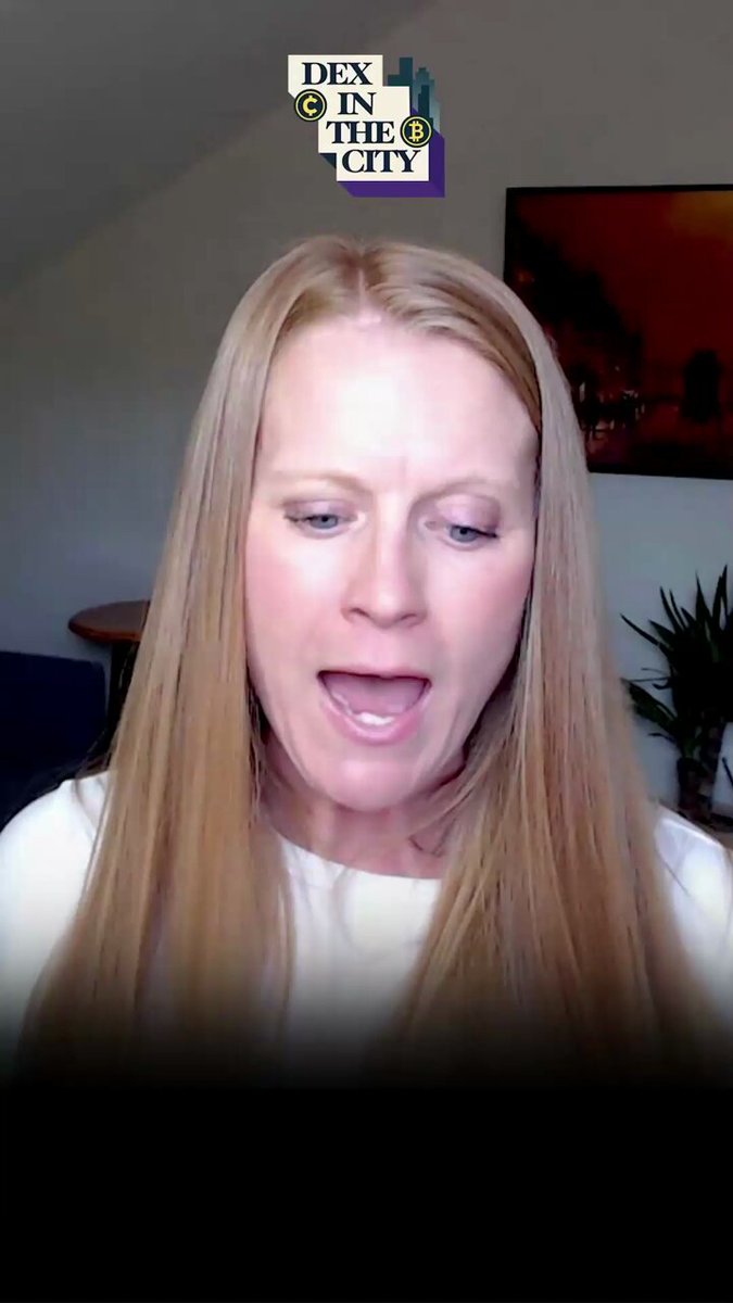 The image shows a woman with blonde hair wearing a white shirt, standing against a brown background. She appears to be making a funny or surprised face while looking at something off-camera. The caption of the image includes some text about cryptocurrency and a reference to a tweet by @kkirkbos.