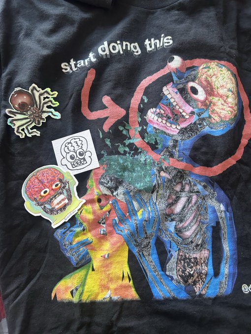 A black art-tee features a colorful horror-style illustration of grotesque skeletal and monster figures with exposed brains and teeth, accompanied by stickers of an eyeball spider and skull, with the text "start doing this" displayed at the top. The shirt relates to the post as a gift from artist @davidvnun, showcasing his distinctive dark, surreal artistic style shared through NFT work.