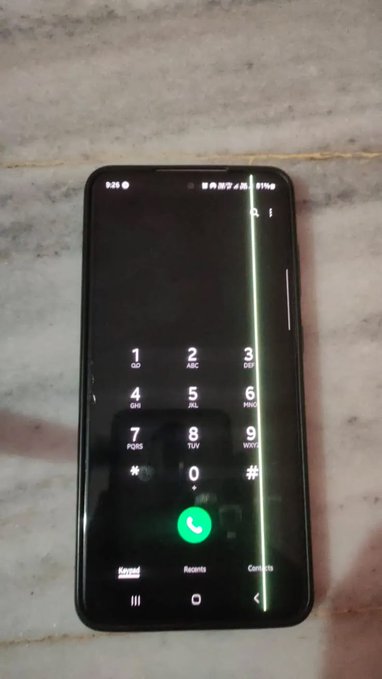 A smartphone displaying a phone dialer app on a marble surface, with a visible green vertical line screen defect running down the right side of the display.