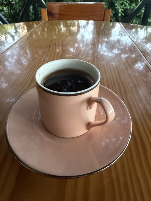 The image features a pink coffee cup sitting on top of a wooden table, along with a matching saucer. There are no other objects or people visible in the scene. The photo appears to be taken from an angle that emphasizes the cup's position at the center of the frame. The caption provided seems unrelated and does not provide any context about the image.