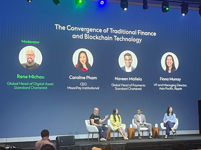 A panel discussion titled "The Convergence of Traditional Finance and Blockchain Technology" featuring moderator Rene Michau (Global Head of Digital Asset, Standard Chartered) alongside speakers Caroline Pham (CEO, MoonPay Institutional), Naveen Mallela (Global Head of Payments, Standard Chartered), and Fiona Murray (VP and Managing Director, Asia Pacific, Ripple), as they sit on stage engaging in conversation.