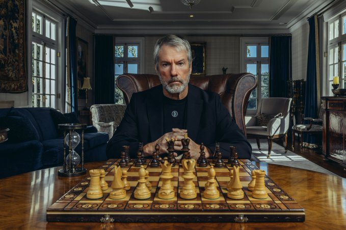 A gray-haired man with a beard sits at a polished wooden table in an elegant room, staring intensely forward with hands clasped behind a wooden chess set, an hourglass visible to the side.