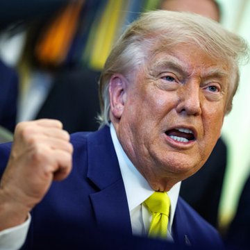 The image shows a man wearing a suit with a yellow tie, giving him an air of authority or importance. The man appears to be making a fist gesture, possibly expressing his disagreement or frustration about something. In the background, there are people present who might be involved in the political situation depicted in the photo. The post also mentions Bitcoin's recent increase and its market cap growth, which could be related to the political events taking place.