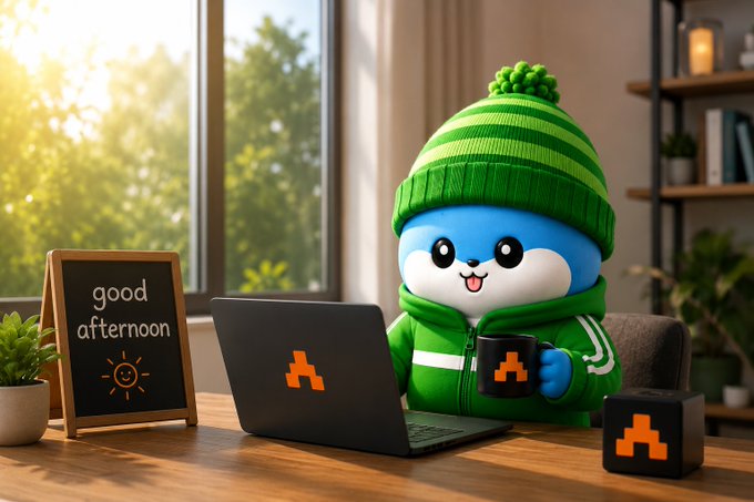 The image features a cute cartoon character, likely a small animal or a doll, sitting at a desk with a laptop computer open in front of them. The character appears to be wearing a green sweater and holding a coffee mug. There are also two potted plants on the desk, one near the left side and another towards the right side. A sign is placed next to the character that says "Good afternoon guys let's talk about @TheARCTERMINAL for a second. Feels like the next AI race may not be about who builds the smartest model. It might be about trust. Who owns the data? Who controls the execution?".