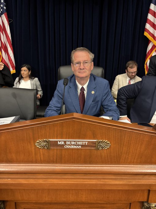 Chairman Mr. Burchett presides over a congressional hearing on DOGE-related fraud in food stamps, with an American flag visible in the background as the gavel drops to officially begin the proceedings.