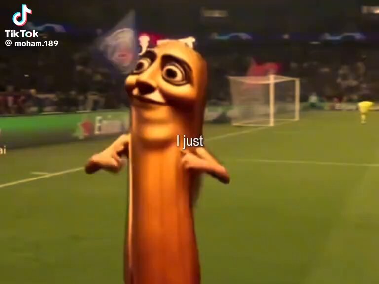 The image features a cartoon character, likely a hot dog or pretzel, standing on a soccer field with a caption that reads "I just" above its head. The scene includes several people scattered around the field, possibly players or spectators. There is also an element of humor in the image as it appears to be a photo manipulation or edited image, with the caption suggesting that someone has added the text "TripleT worldcup".