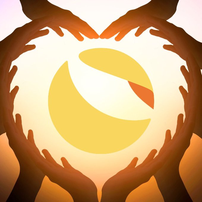 Silhouetted hands form a heart shape around a glowing yellow and orange sphere, symbolizing love, support, and hope—perfectly capturing the sentiment of a community rallying for $LUNC's potential historic comeback.