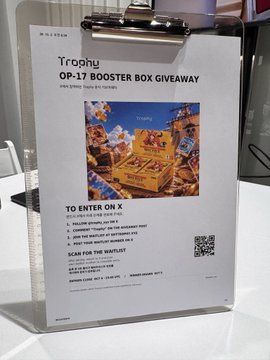 A sign advertises an OP-17 Booster Box Giveaway at a TCG store, with instructions to enter on X and scan a QR code for the waitlist.